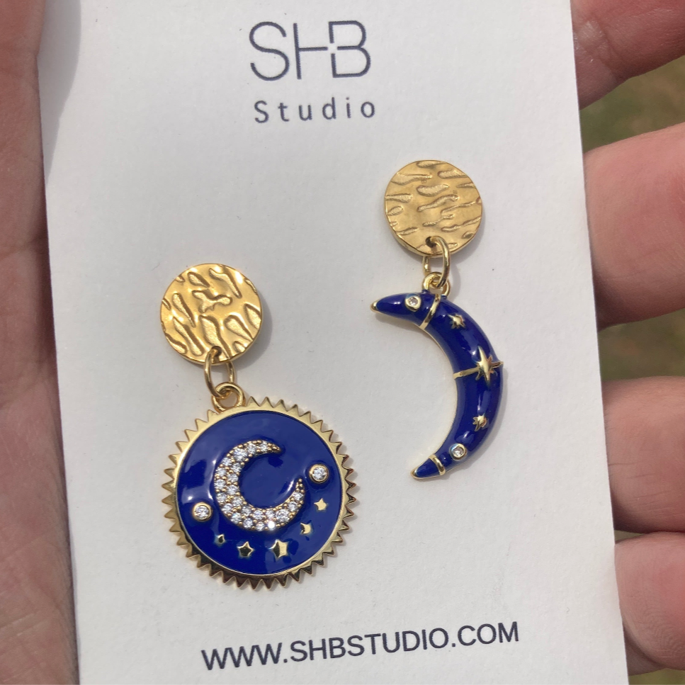 Blue and gold earrings on a card with SHB Studio branding.