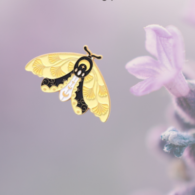 Moth brooch on a blurred floral background with promotional text.