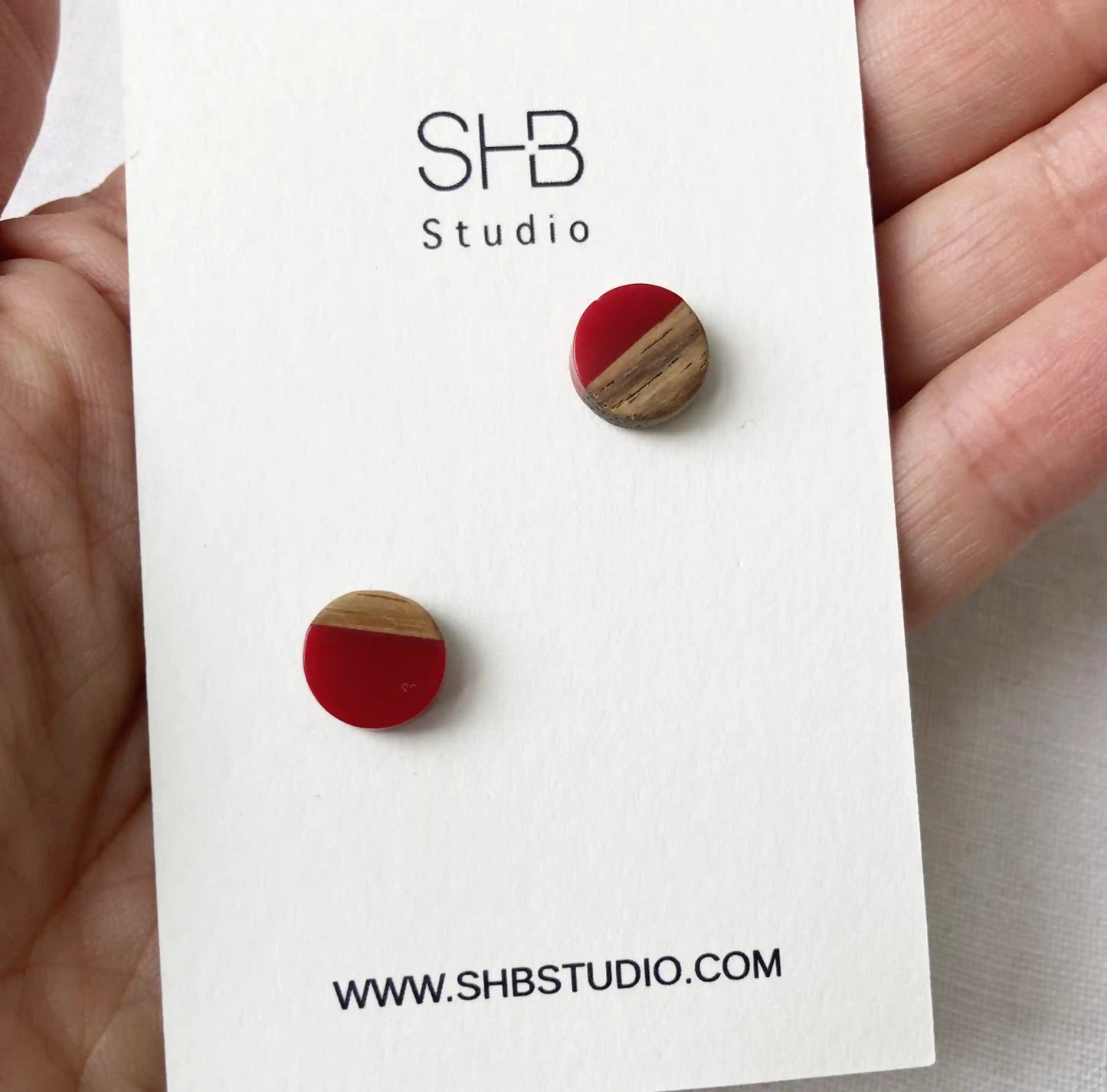 Half Wooden and halfdark red colour resin earrings on a SHB Studio card.