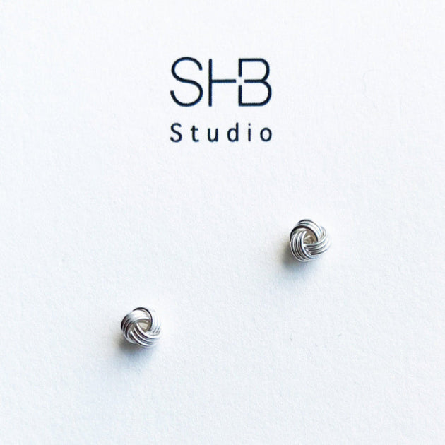 A pair of sterling silver knot stud earrings displayed against a white background with 'SHB Studio' logo.