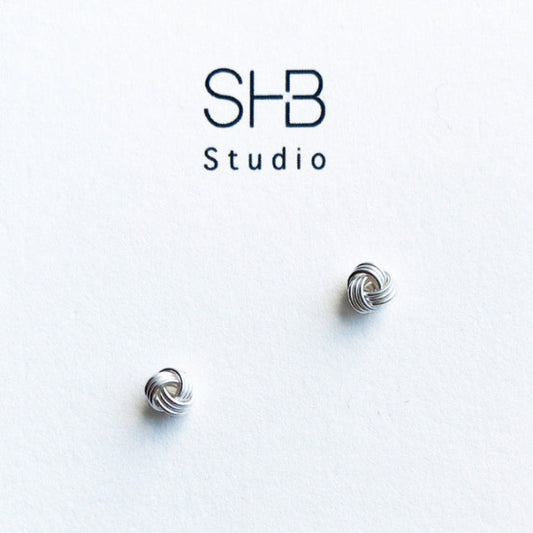 A pair of sterling silver knot stud earrings displayed against a white background with 'SHB Studio' logo.