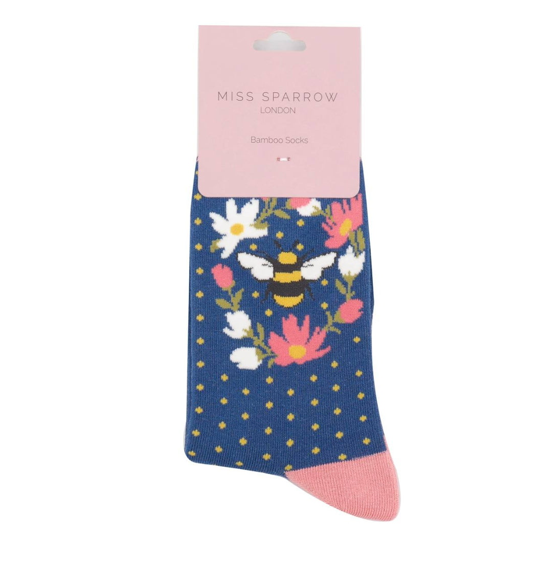 Floral and bee-patterned sock with pink heel, navy blue body, and pink packaging on a white background