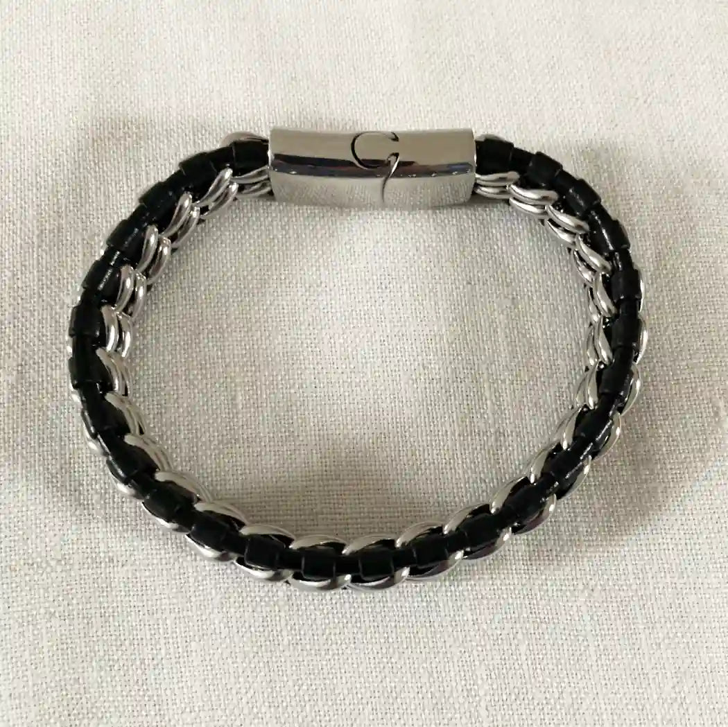 Black and silver made by stainless steel and leather bracelet on a light beige background