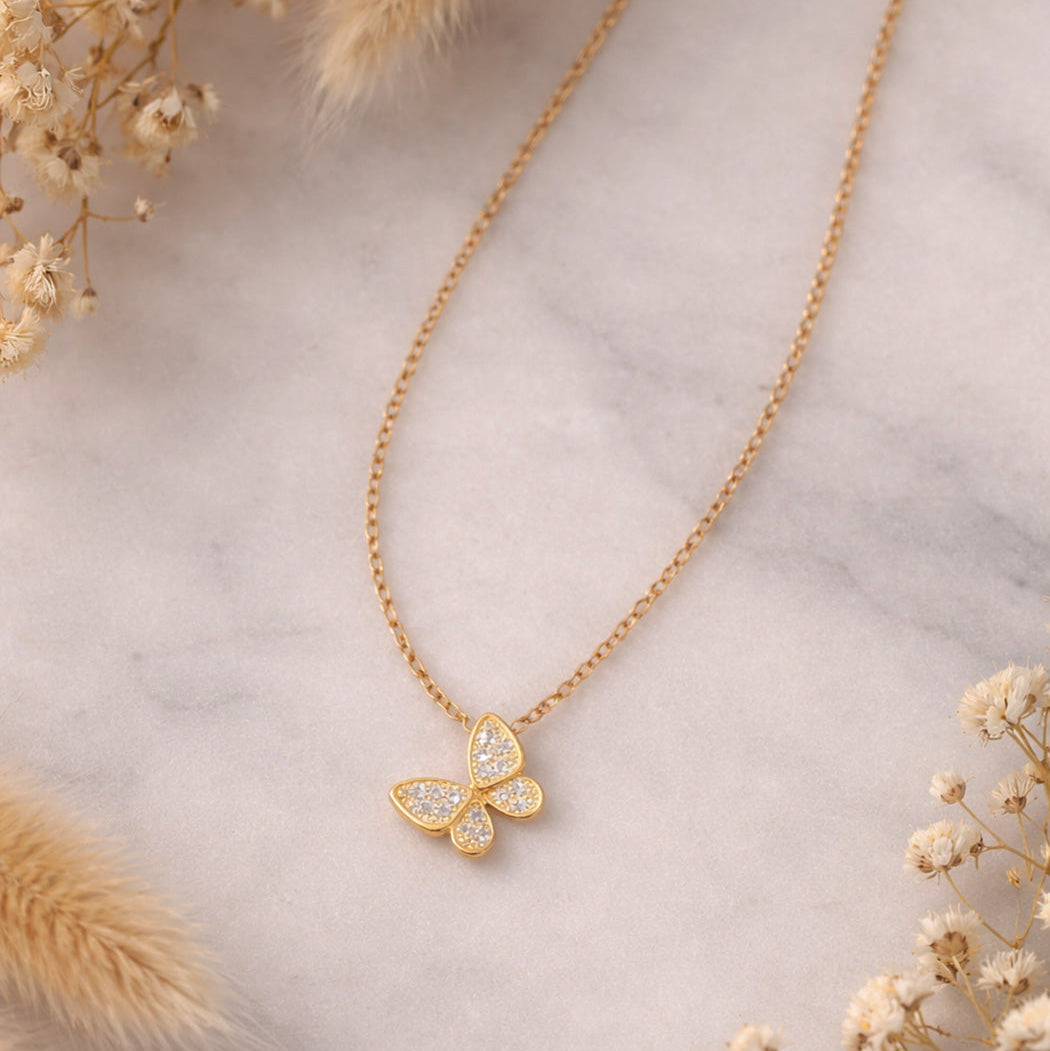 waterproof and hypoallergenic gold butterfly pendant with zirconia on minimal background