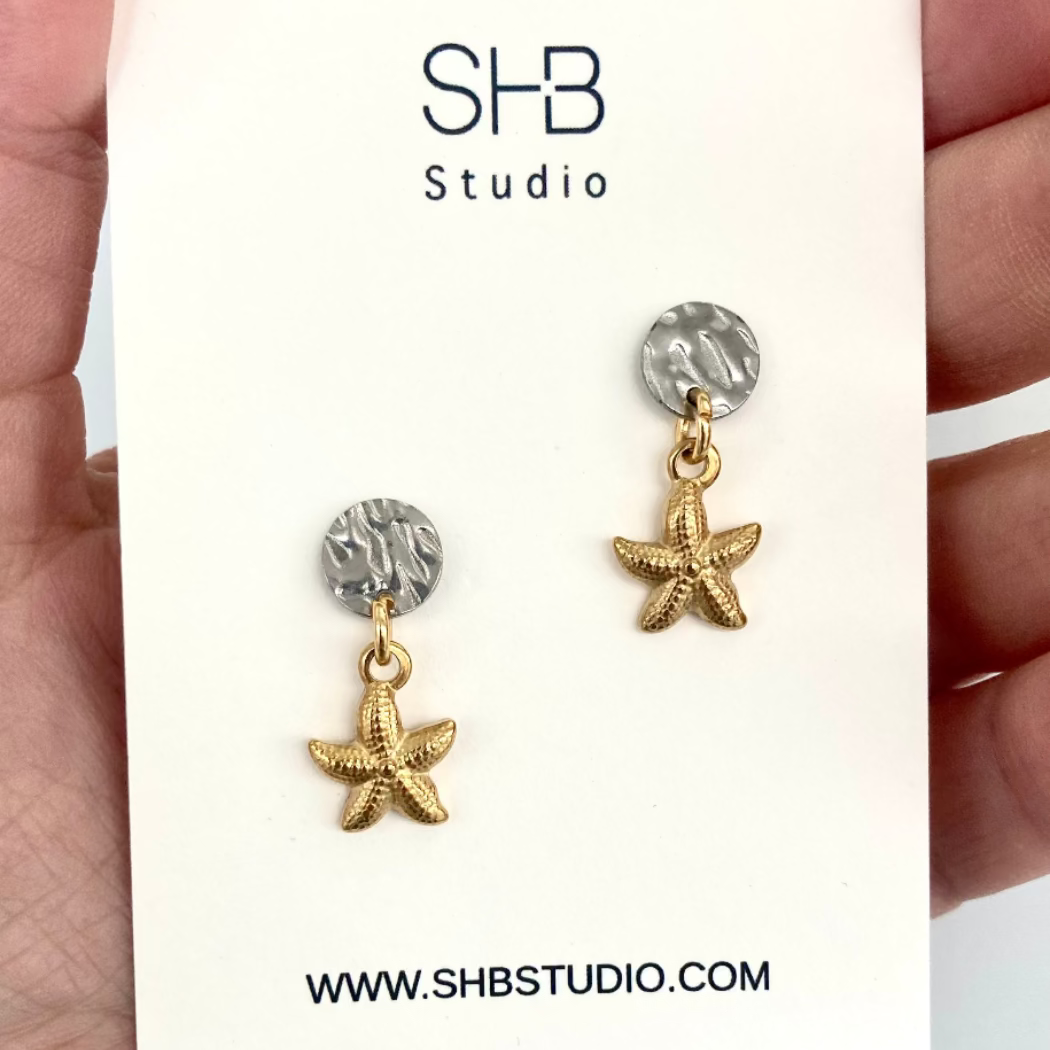 Starfish-shaped earrings with gold and silver details on a white card with SHB Studio branding.