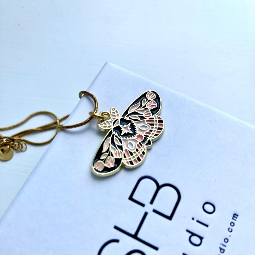 Butterfly-shaped pendant on a white card with text