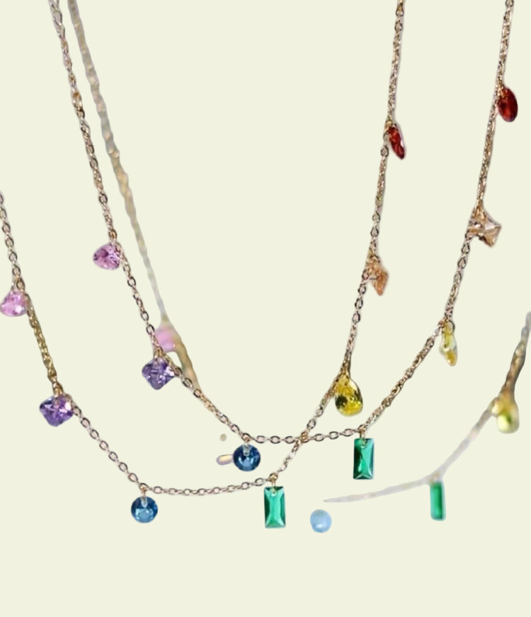 Gold necklaces with colorful gemstones on a blurred background