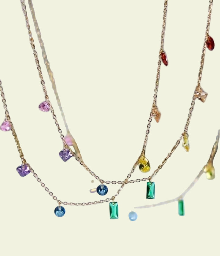 Gold necklaces with colorful gemstones on a blurred background