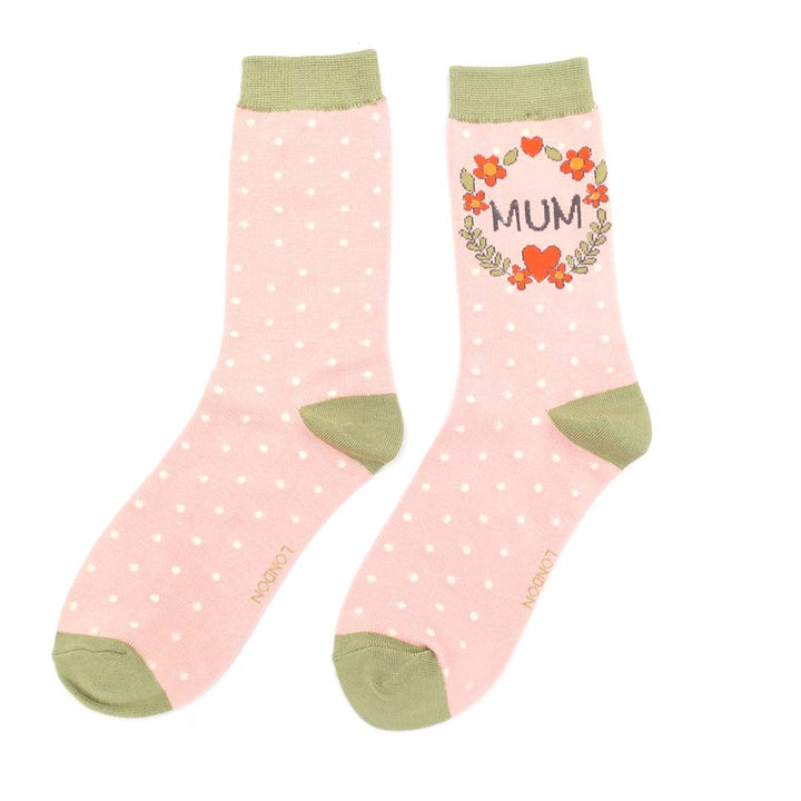 Pink polka dot socks with green accents and floral design on a white background