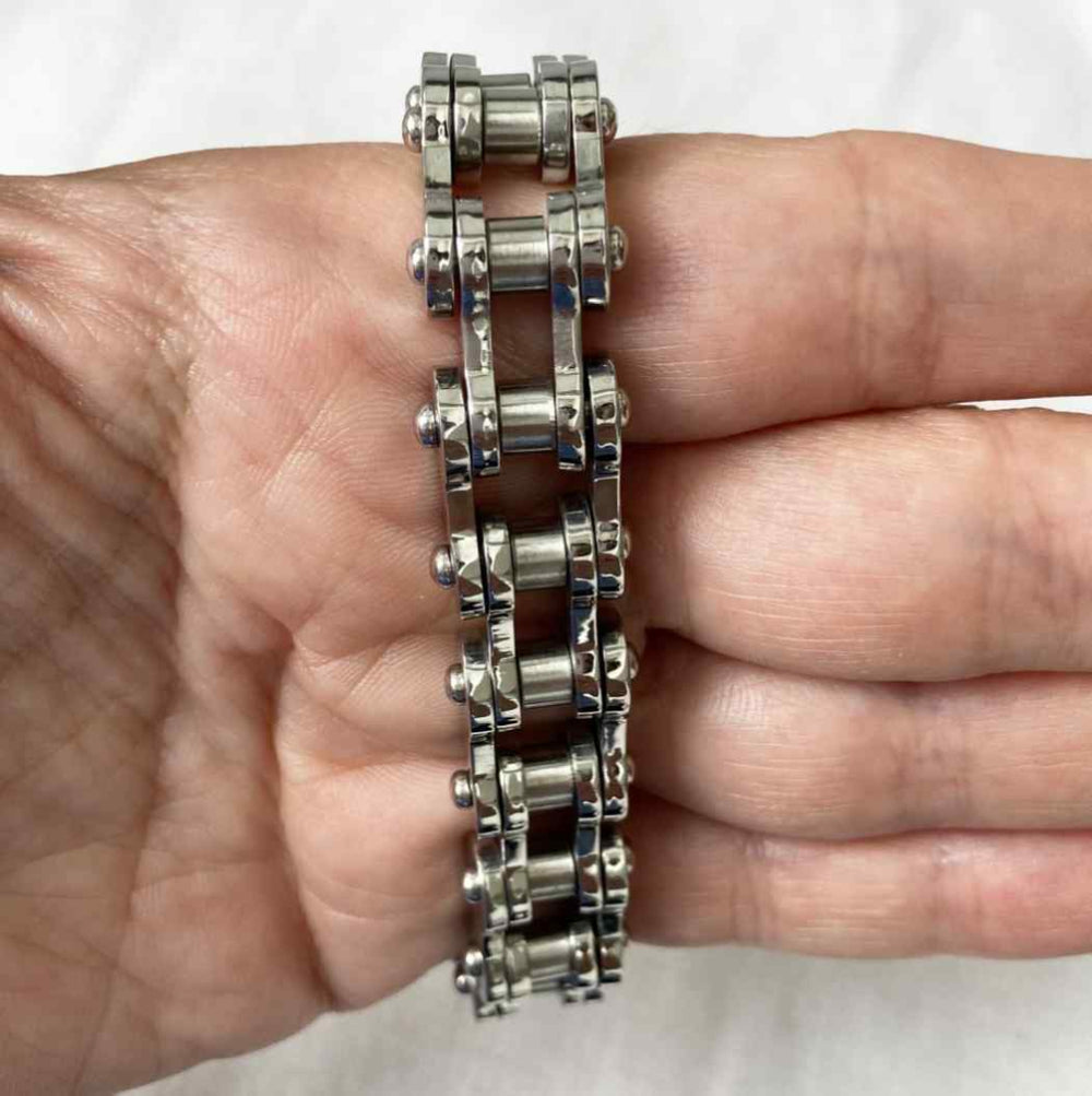 Metallic chain bracelet on a person's wrist against a white background