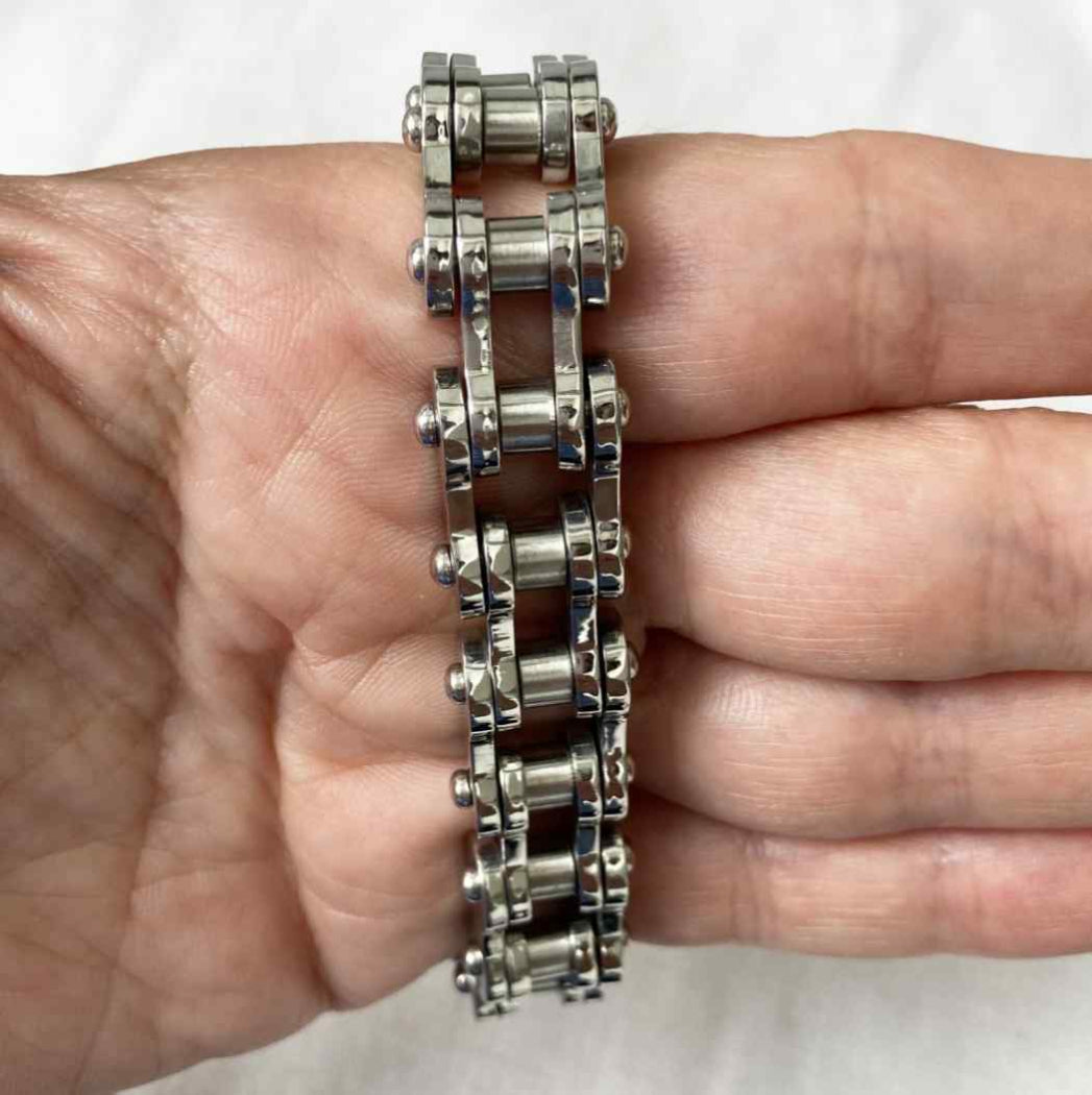 Metallic chain bracelet on a person's wrist against a white background
