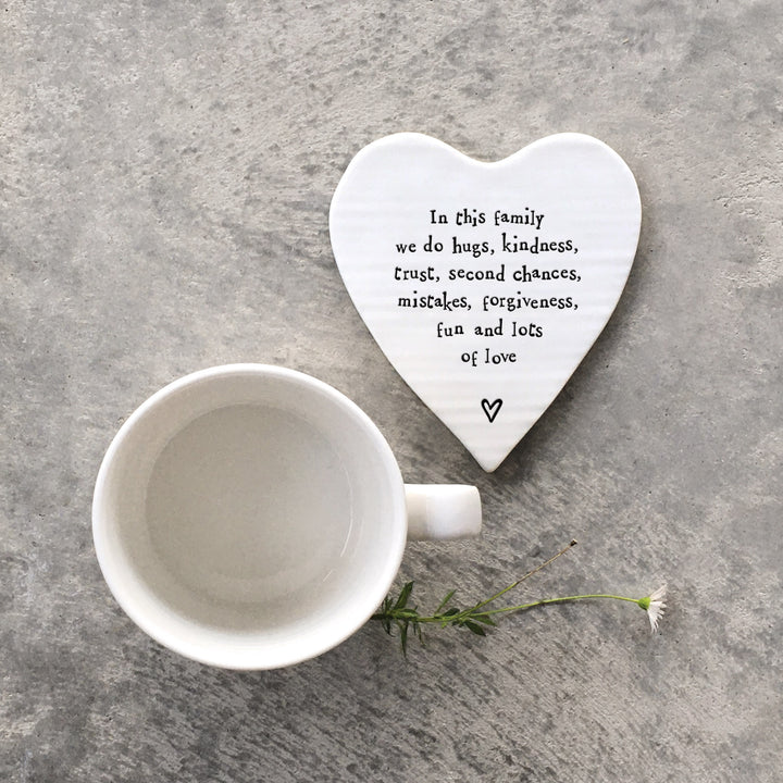 Heart-shaped porcelain coaster with text and a white mug on a gray surface