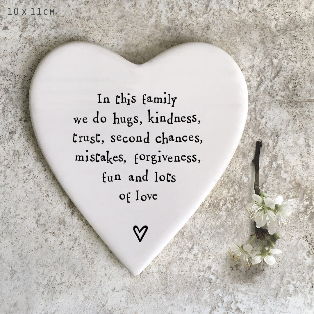 Heart-shaped porcelainplaque with family values text on a textured surface with flowers.