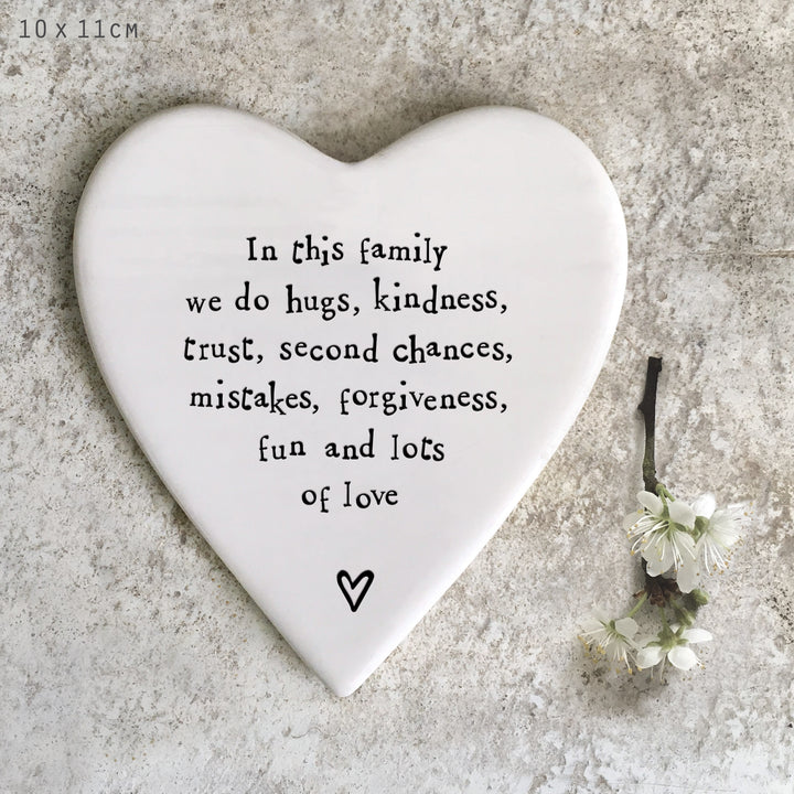 Heart-shaped porcelainplaque with family values text on a textured surface with flowers.