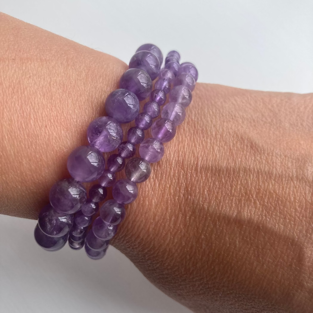 Purple beaded bracelet on a wrist against a white background