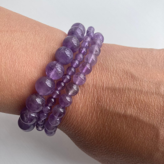 Purple beaded bracelet on a wrist against a white background