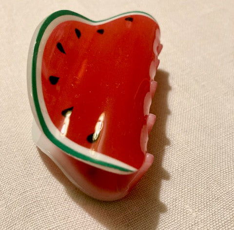 Watermelon-shaped hair claw on a beige fabric background