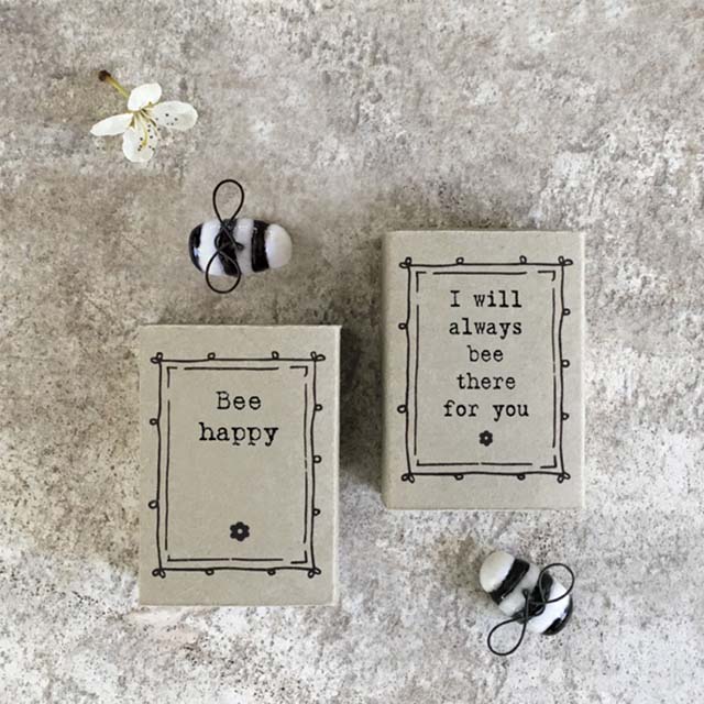 Two small stone blocks with motivational phrases and decorative bees on a textured surface.