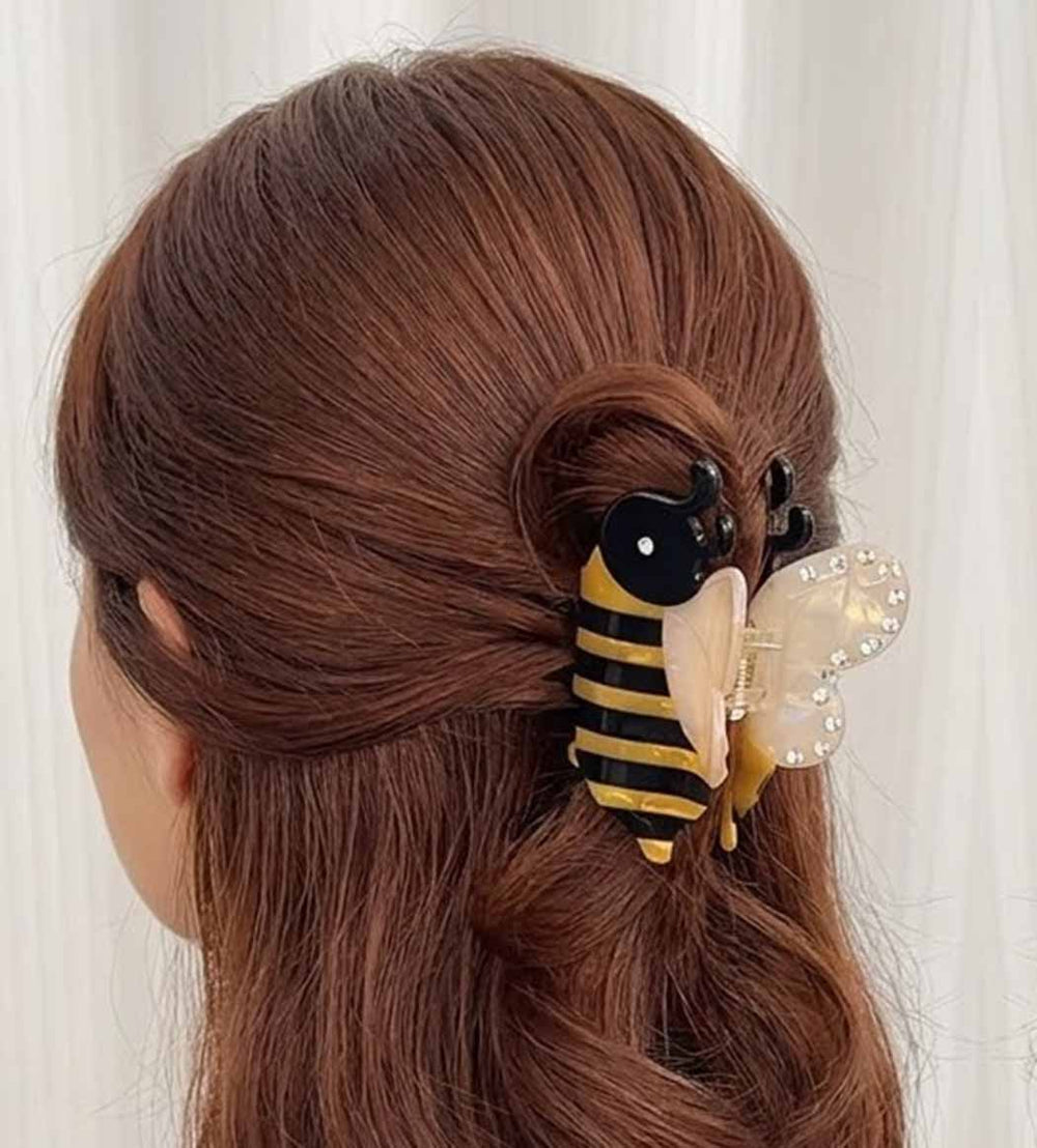 Hair accessory shaped like a bee with a butterfly on brown hair against a white background