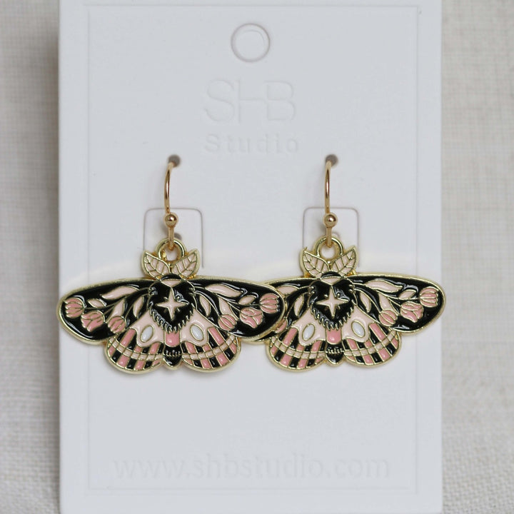 Butterfly-shaped earrings on a white card with &