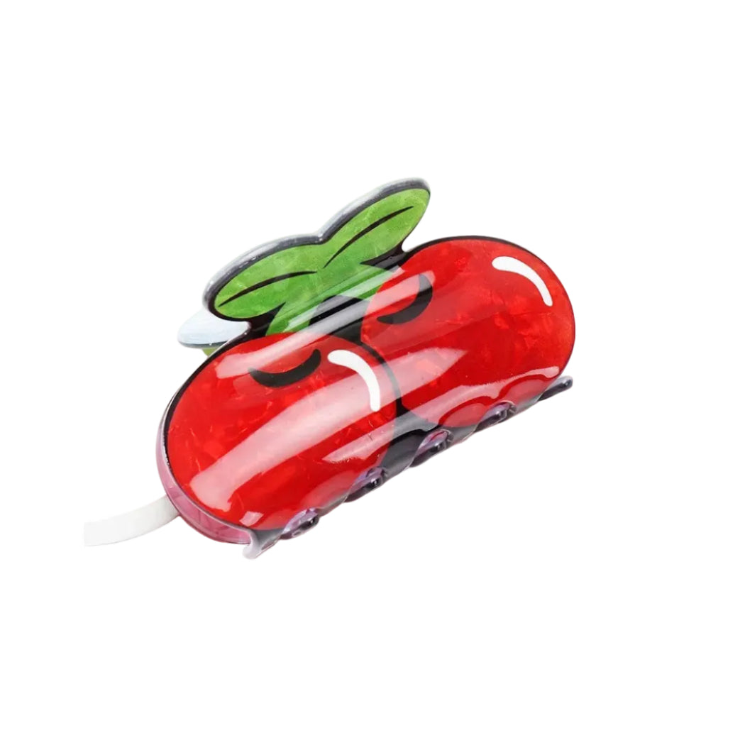 Red cherry-shaped hair clip with a green leaf on a white background