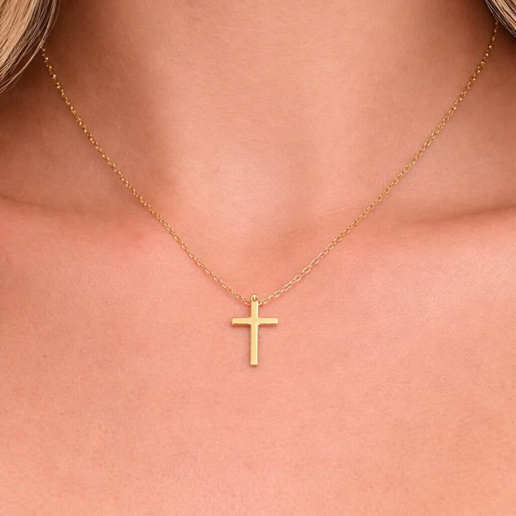 Gold cross necklace on a person's neck