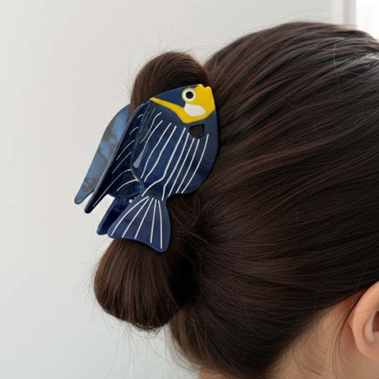 Person wearing a blue fish-shaped hair clip on a white background