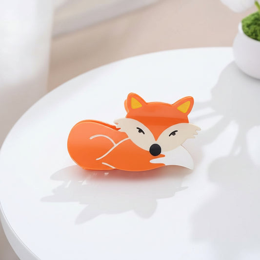Fox-shaped hair claw stand on a textured surface with decorative elements in the background 