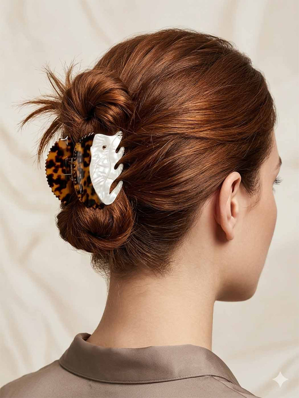 Woman with styled hair featuring a decorative hair clip against a neutral background