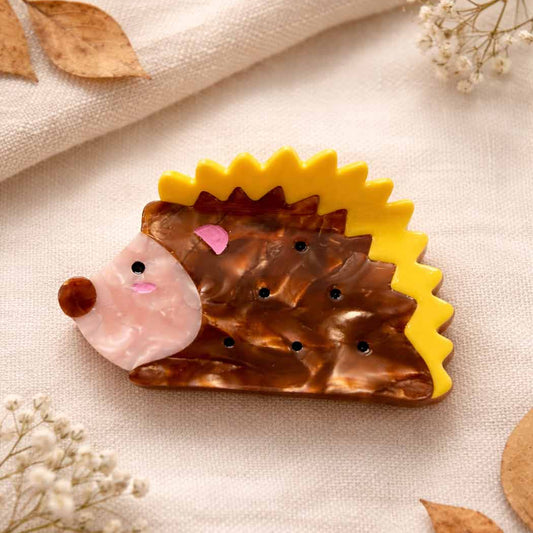hedgehog  hair claw on cream background with leaf around corners.