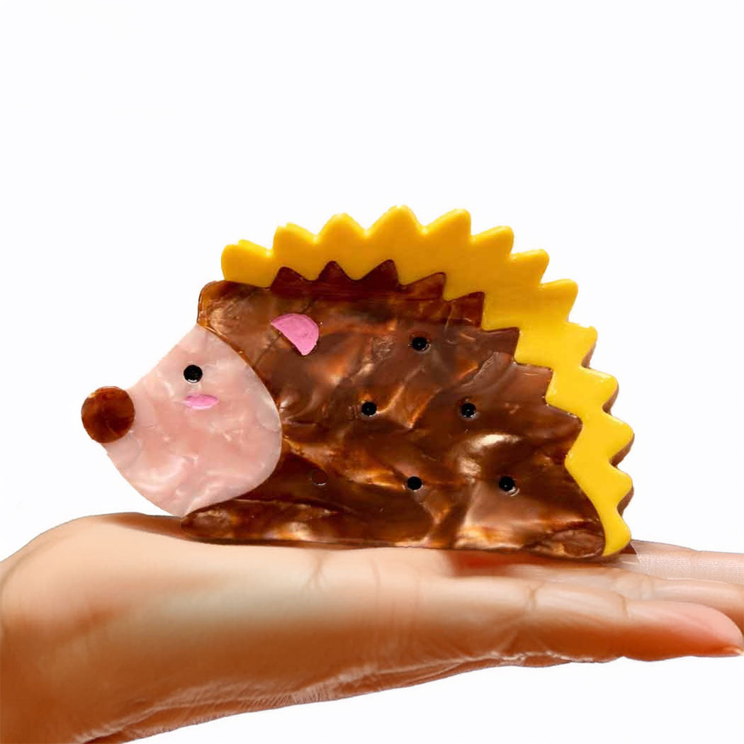 Hedgehog-shaped toy with a yellow back on a hand against a white background