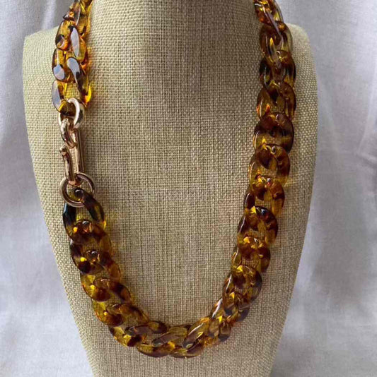 light leopard acrylic necklace on a beige fabric stand with a white background