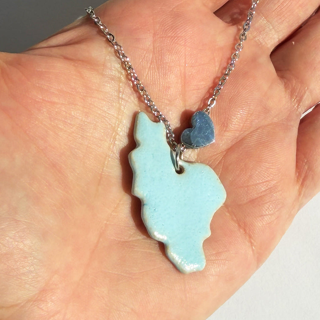 Necklace with a light blue iran map handmade ceramic pendant on a hand