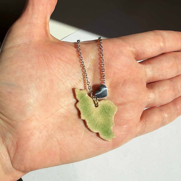 iran map ceramic necklace light green crack glazed shows on hand.