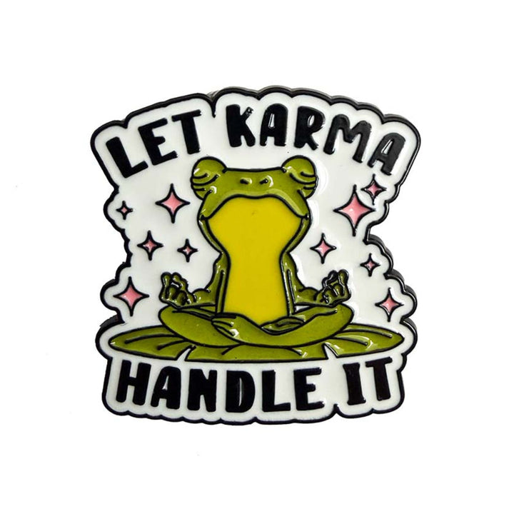 A die-cut enamel pin featuring a green frog meditating in a pond with pink sparkles, surrounded by the text &