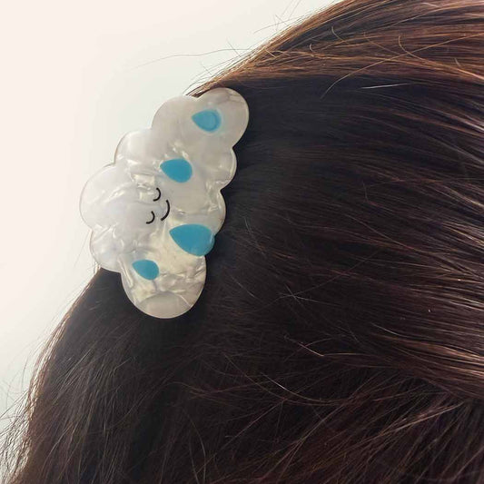 Hair clip with cloud design and blue accents on a person's hair against a white background