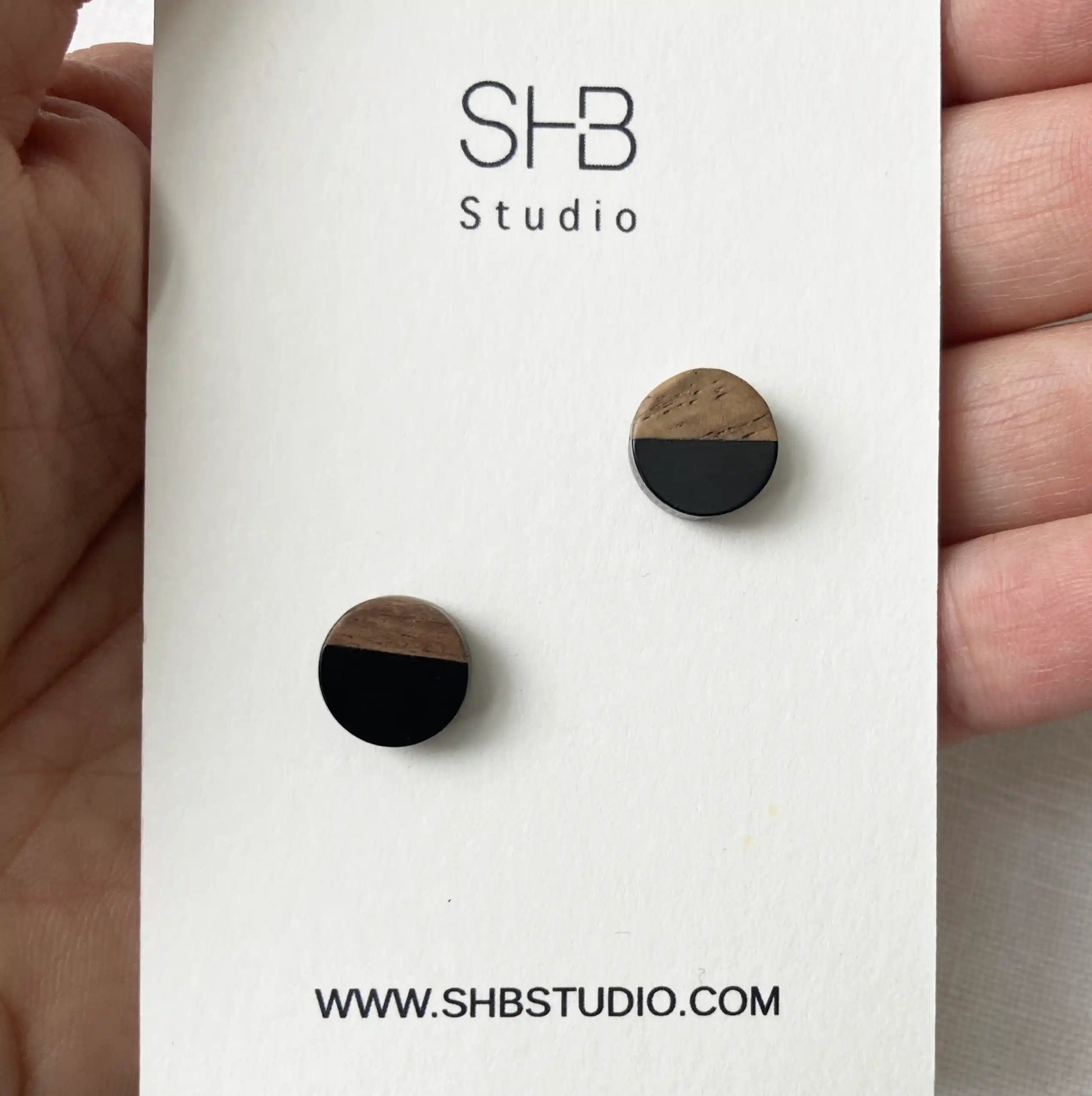 Wooden earrings  studs half black half wood design on a SHB Studio branded card.