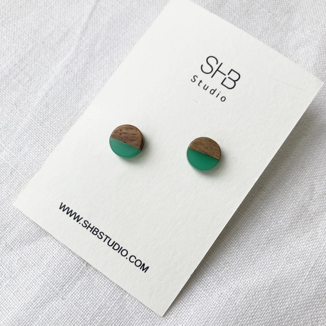 Half Wooden and half light green resin earrings on a SHB Studio card.
