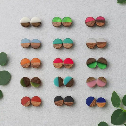 Colorful wooden  and resin earrings displayed on a light gray background with green leaves.