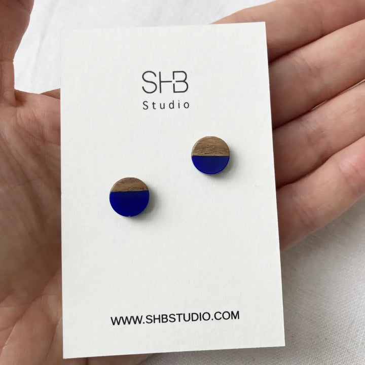 Half Wooden and half navy blue matt colour  resin earrings on a SHB Studio card.