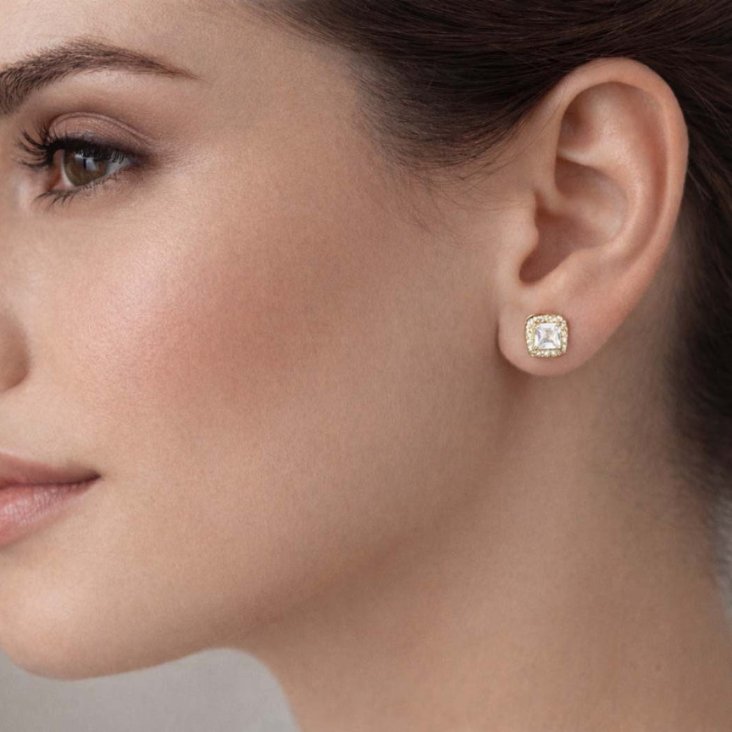 Close-up of a woman wearing a diamond earring against a neutral background