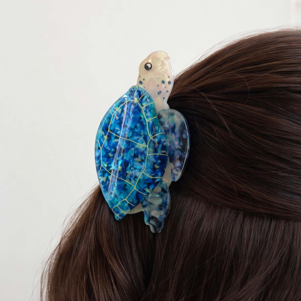 Tortoiseshell-patterned hair clip on a person's hair against a white background