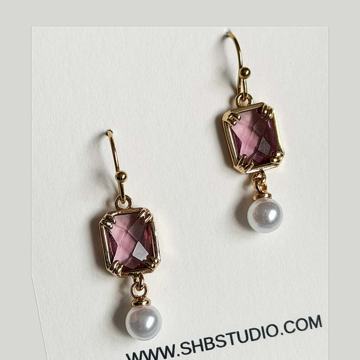 Pair of light purple crystal glass and pearl drop earrings in an 18K gold-plated square setting on an SHB Studio card
