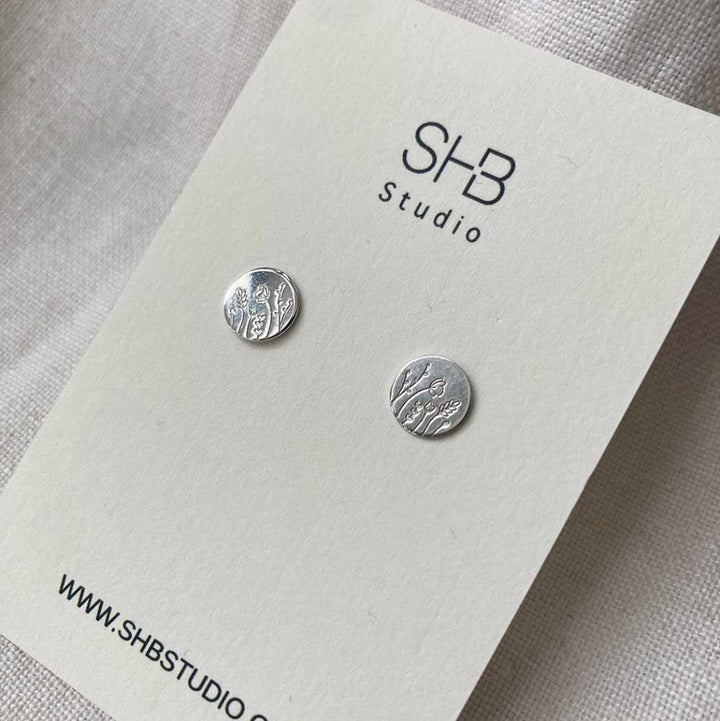Silver round earrings on a SHB Studio branded card.