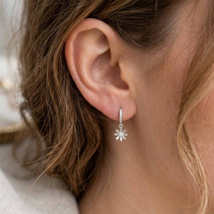 Close-up of an ear wearing a silver flower-shaped earring.