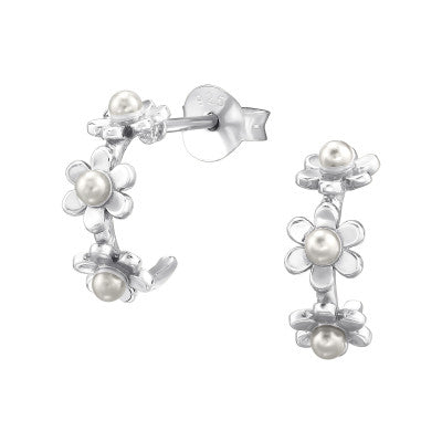 Silver earrings with floral designs and pearls on a white background