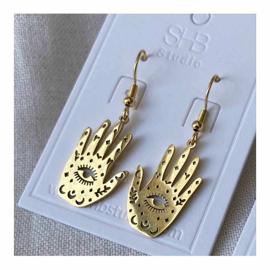 Gold hand-shaped earrings on a branded card