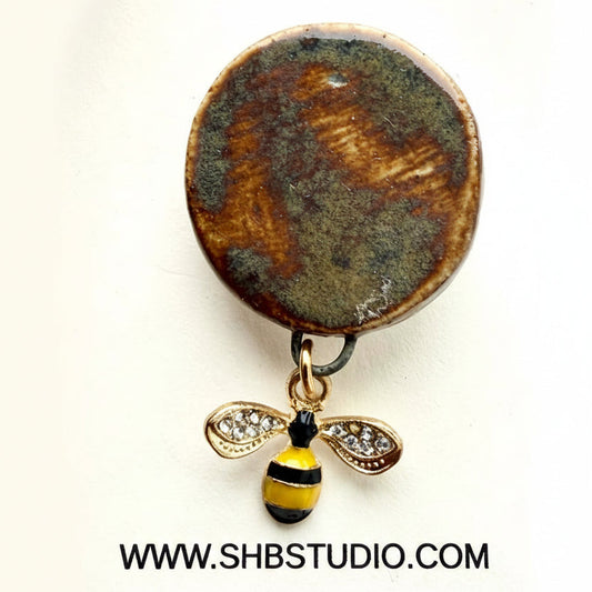 Jewelry brooch with a bee design on a white background, featuring the SHB Studio logo.