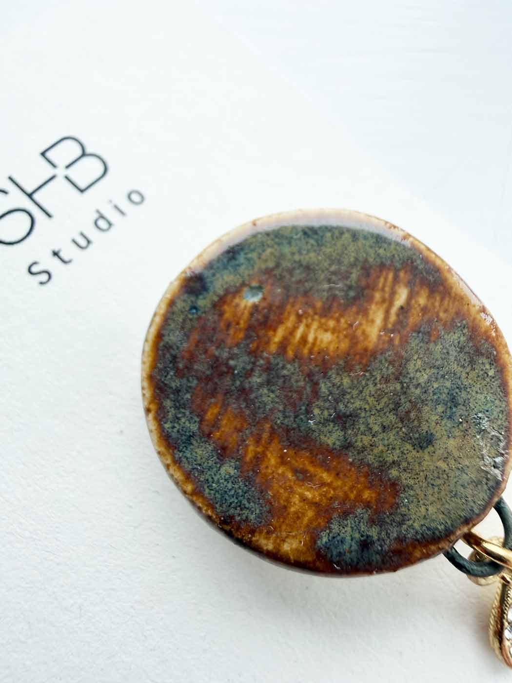 Round ceramic  with brown and green glaze on a white background, featuring &