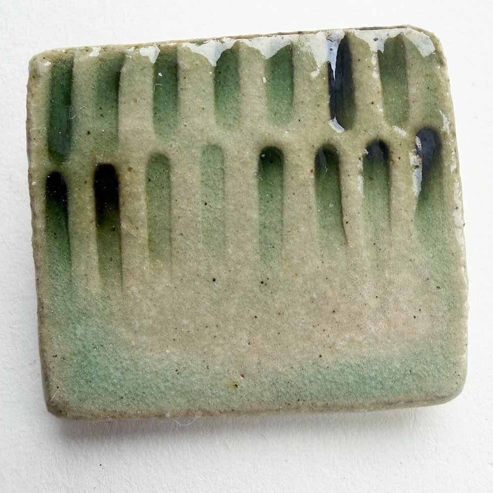 Rectangular ceramic bar with green glaze and ribbed texture on a white background